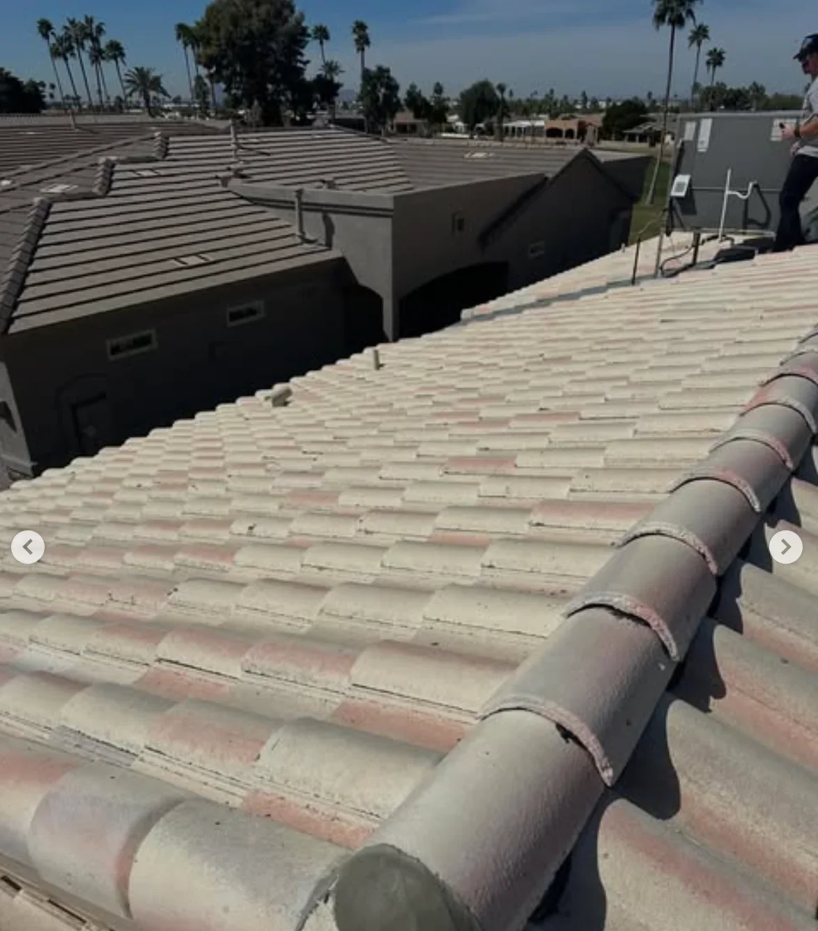 Clay barrel tile roof installation with ridge caps on commercial building