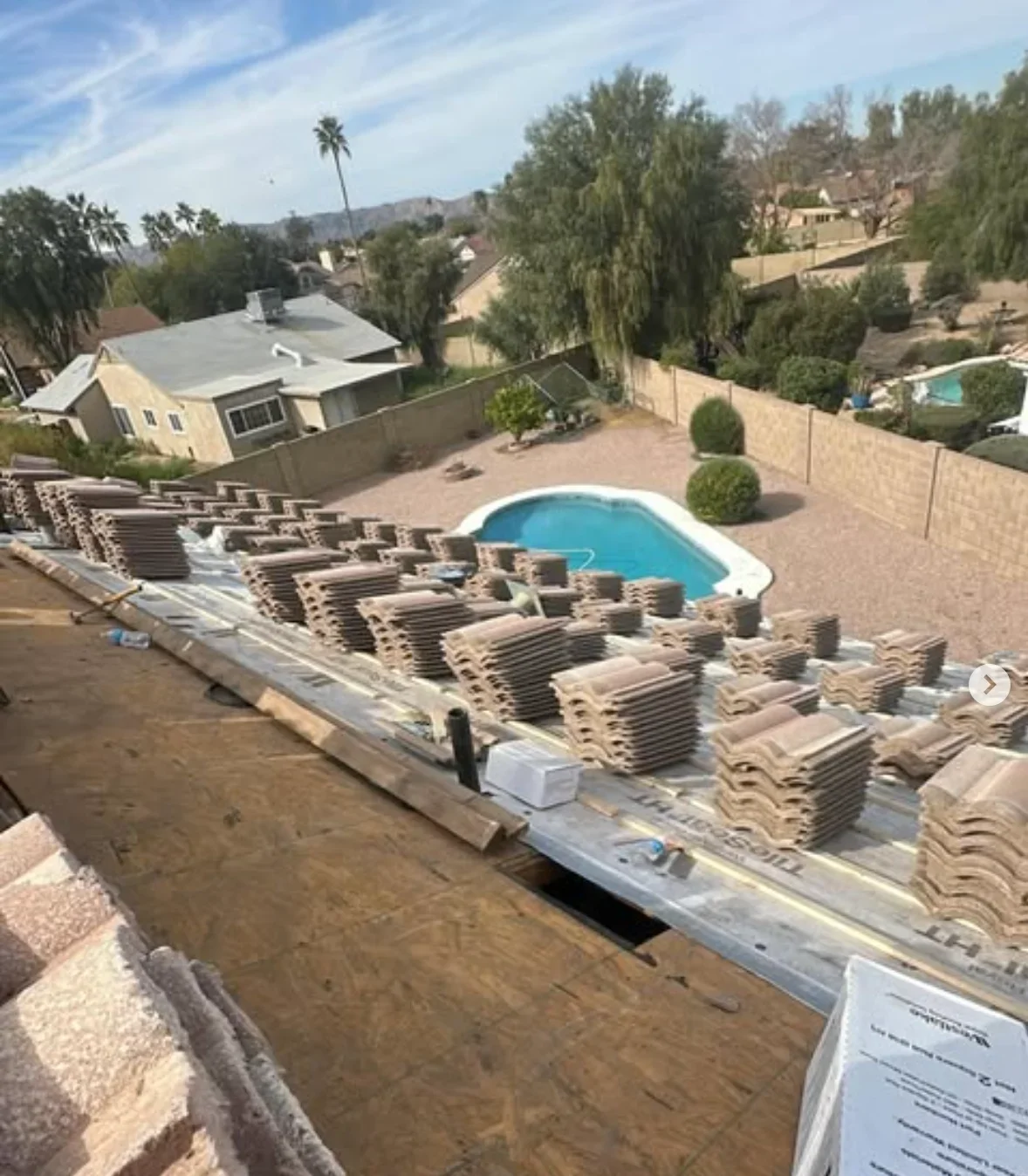 Spanish clay barrel tiles staged for roof installation with white underlayment and flashing visible